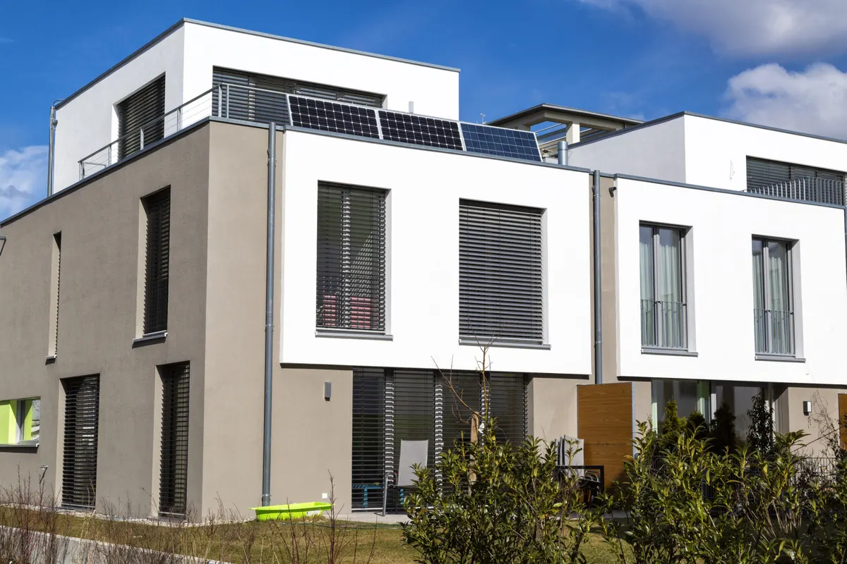 Modernes Mehrfamilienhaus mit weißer Fassade und Photovoltaik