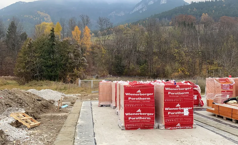 Ziegelpaletten auf der Baustelle vor herbstlichem Wald